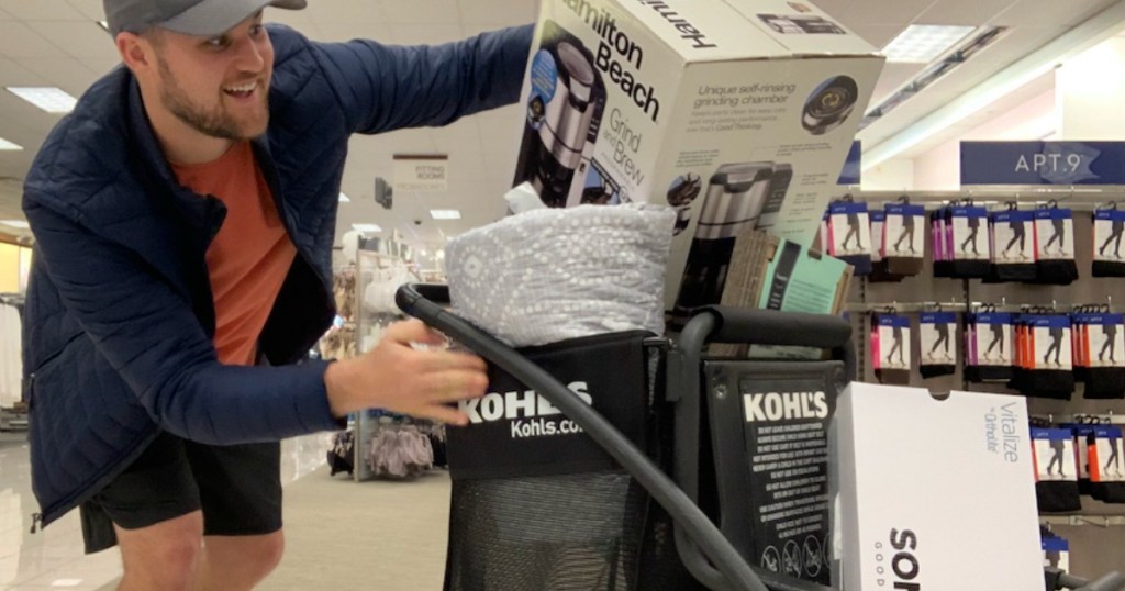 man pushing a kohl's shopping cart filled with merchandise