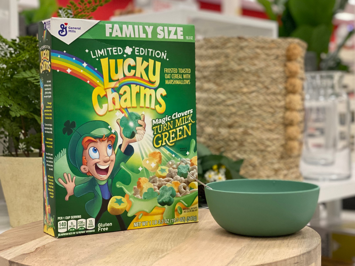 Box of Lucky Charms cereal on a table with a green bowl