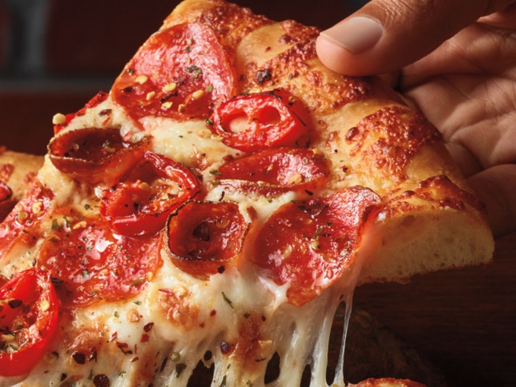 holding a slice of spicy pizza