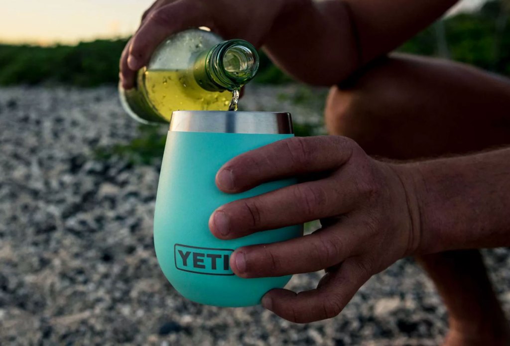 person pouring wine into a blue yeti wine tumbler