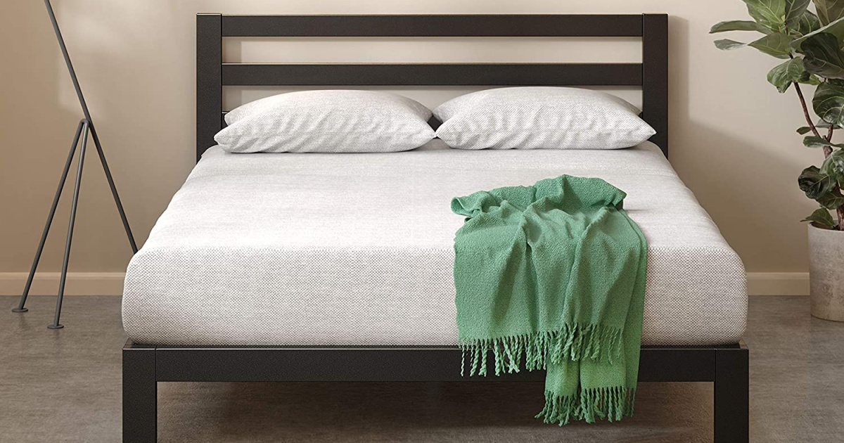 Large metal bed with white bedding and green throw