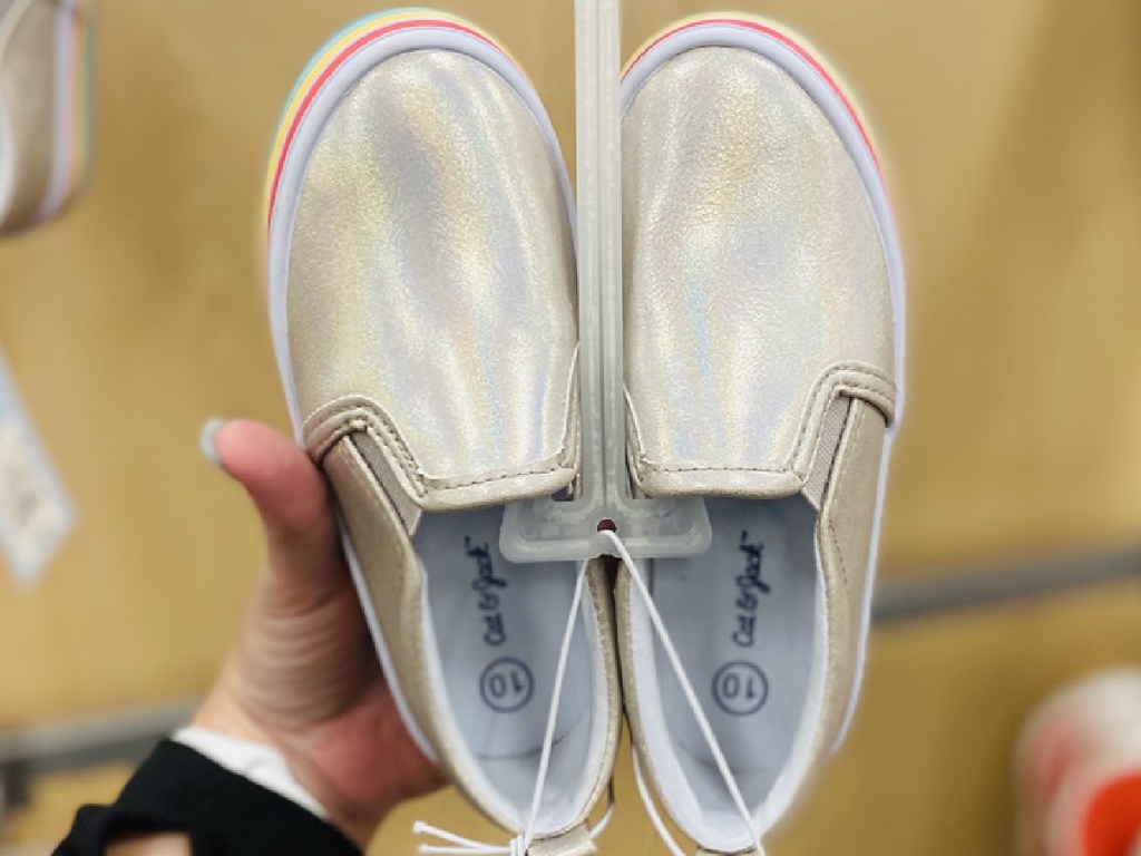 hand holding up pair of shiny shoes in store