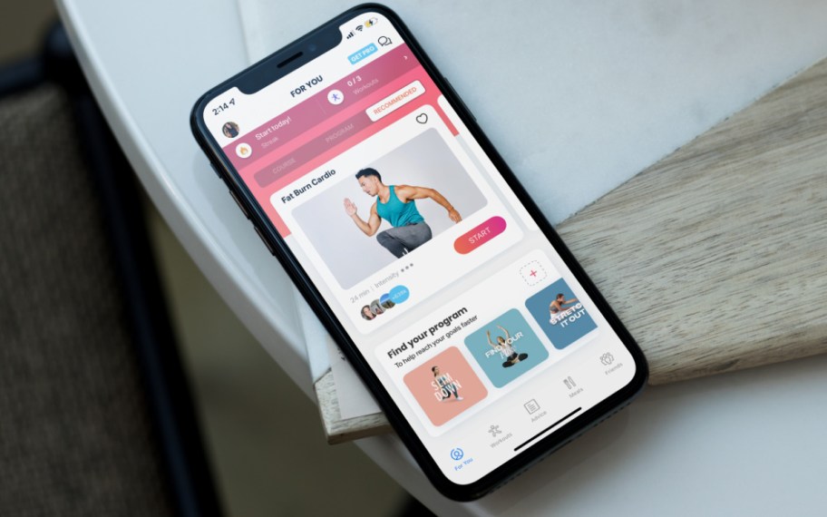 phone laying on table with fitness workout app on screen