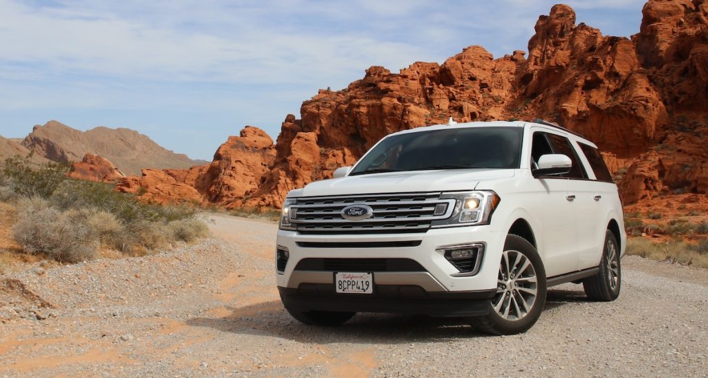 white ford car sitting in desert road 