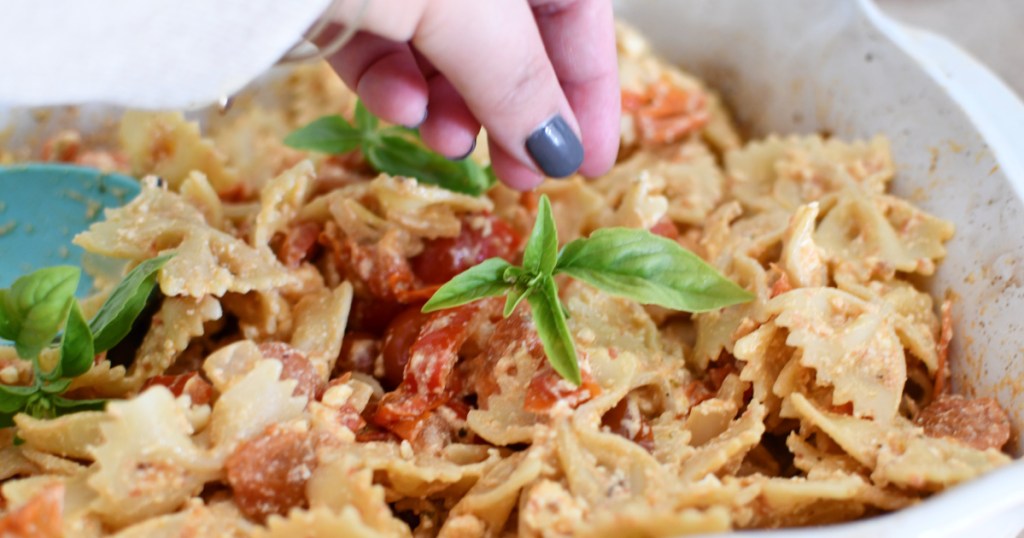 garnishing feta pasta with fresh basil