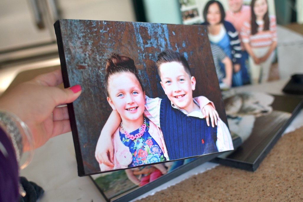 holding DIY photo canvas of 2 kids 