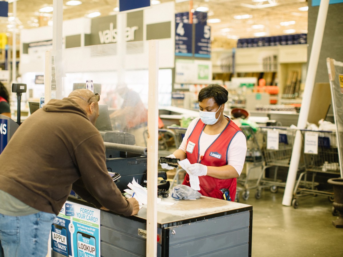 masked Lowe's cashier waiting on customer 