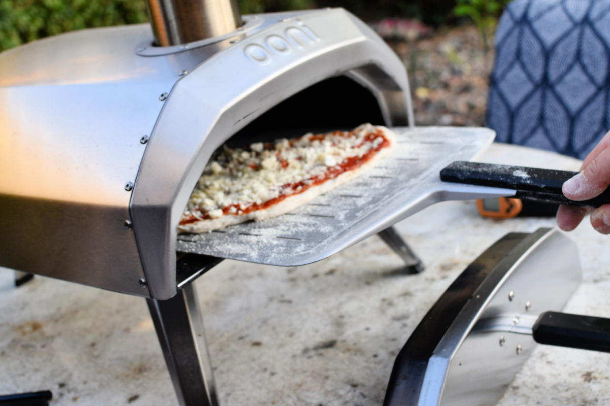 putting a pizza into the Ooni pizza oven 