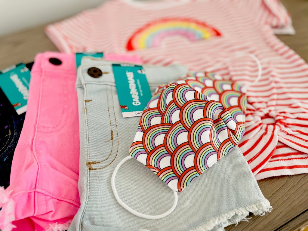 set of colorful shorts rainbow mask and shirt laying on table