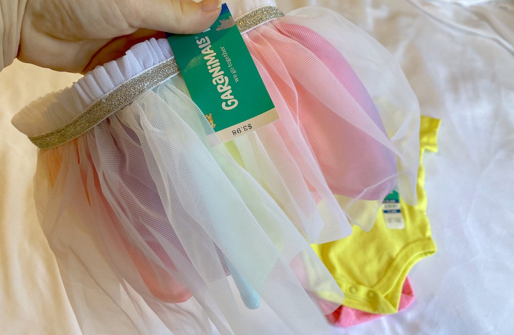 hand holding a rainbow tulle skirt with garanimals tag