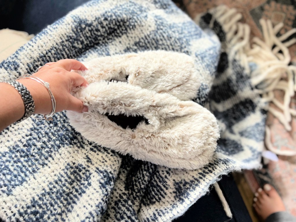 woman holding a pair of warmies slippers