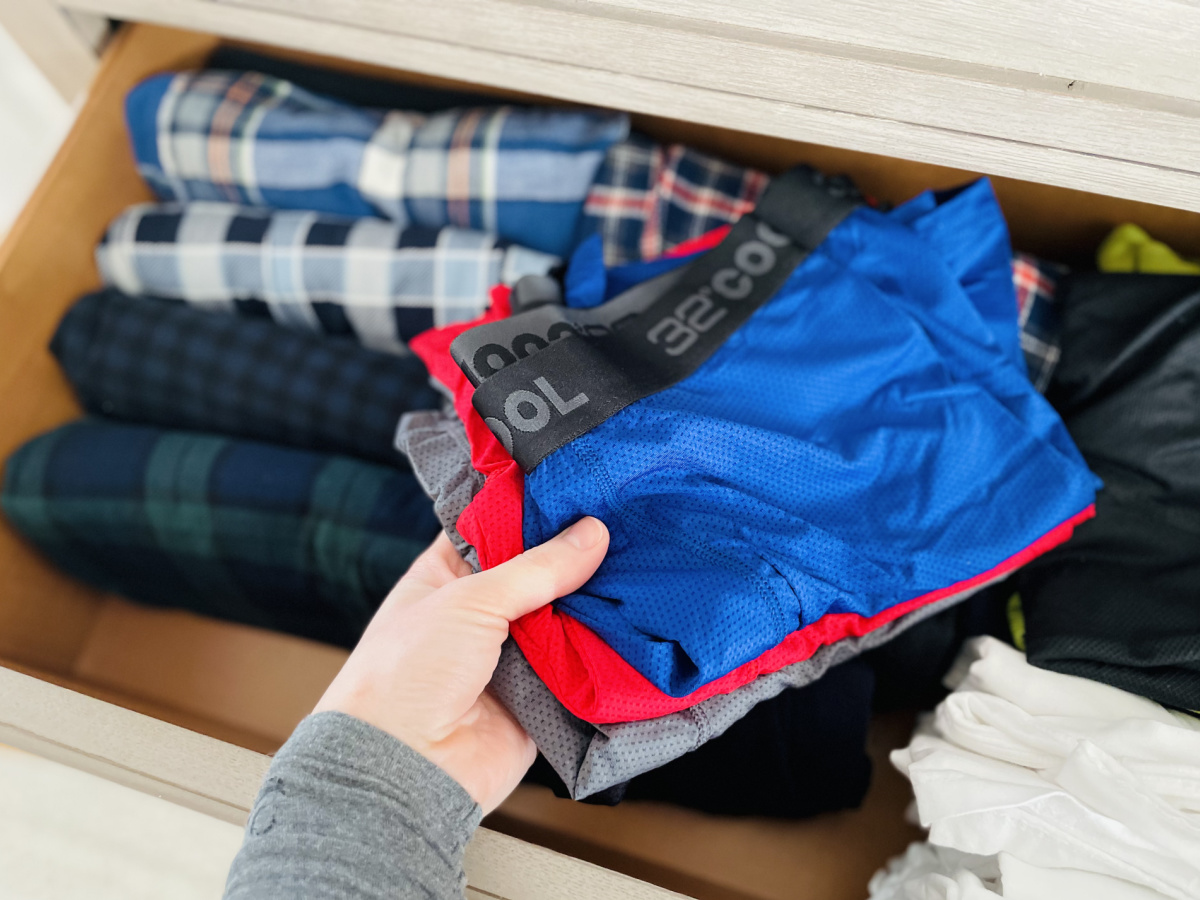 Man's hand grabbing pairs of boxers from dresser drawer