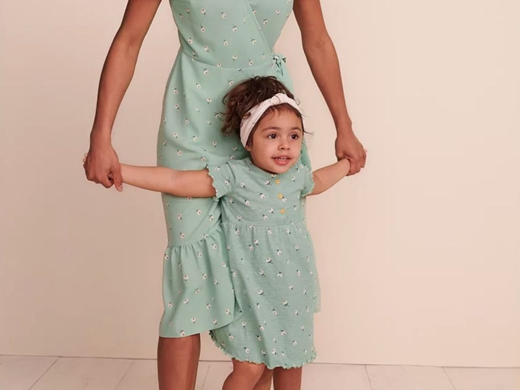 woman holding girls hands both in matching outfits