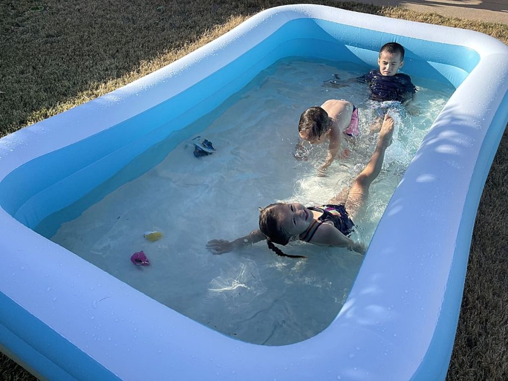 three kids playing in inflatable pool