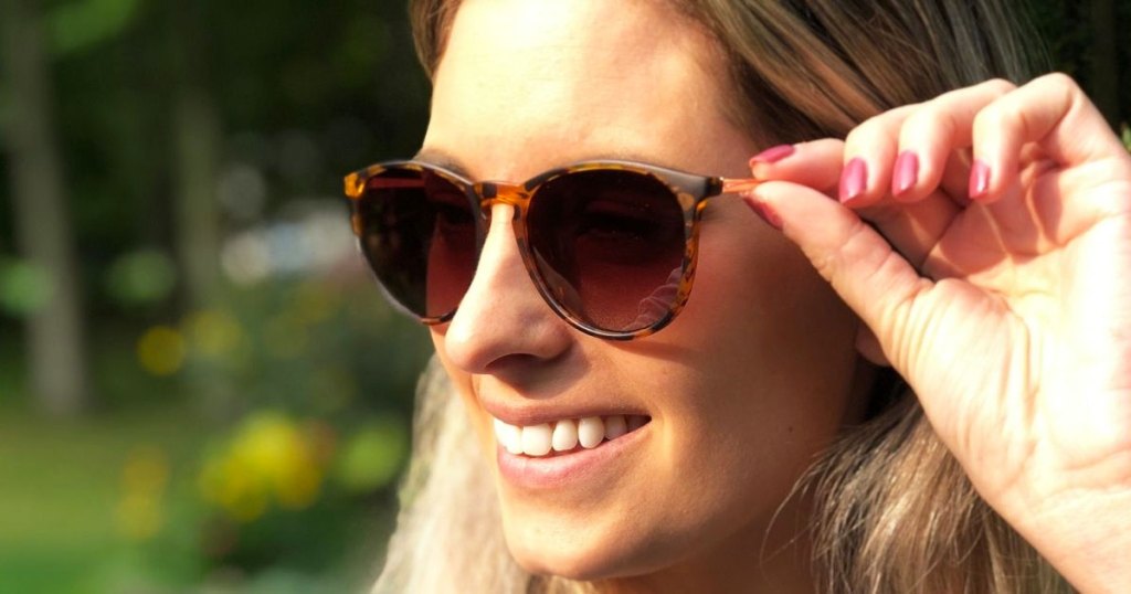 pair holding a pair of sunglasses on her face