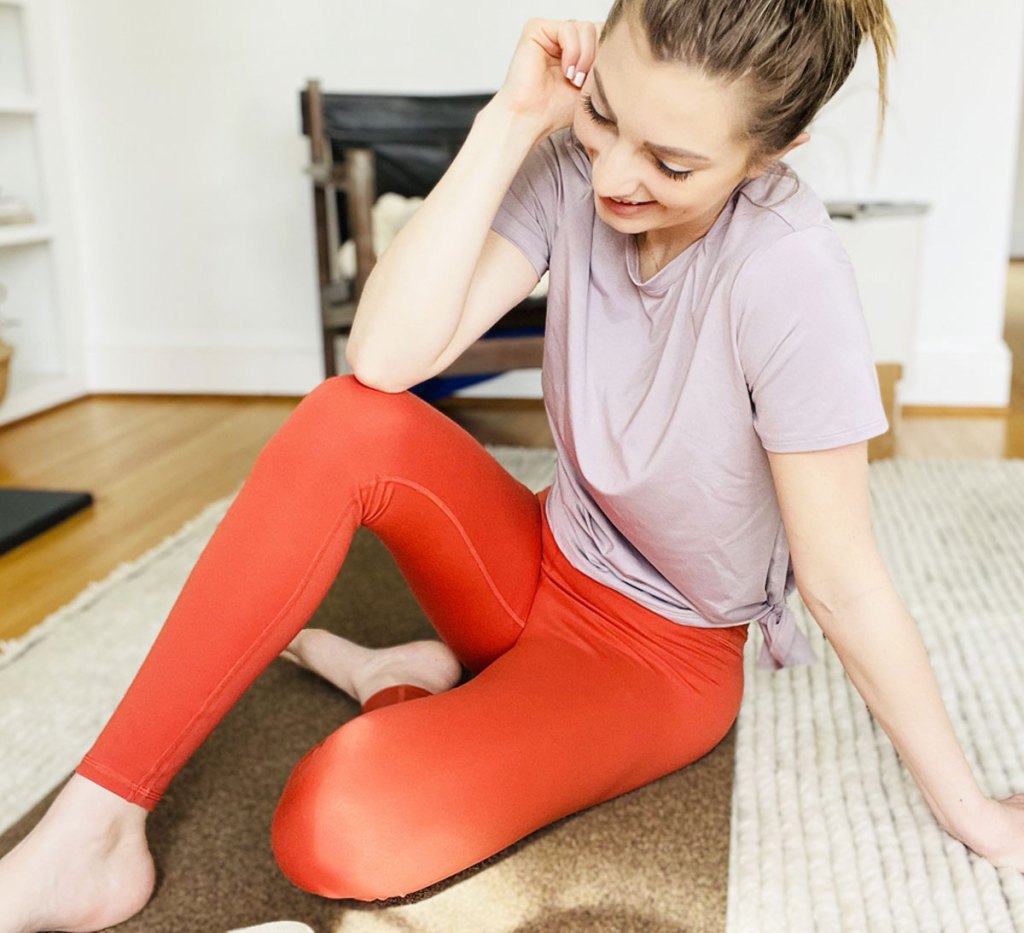 woman sitting on floor wearing orange leggings and pink shirt