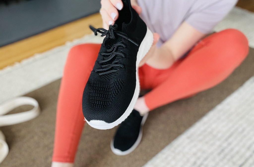 hand holding a pair of black sneakers