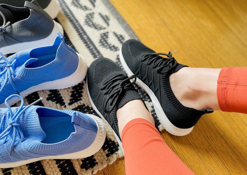 feet wearing black walking shoes next to blue and gray sneakers