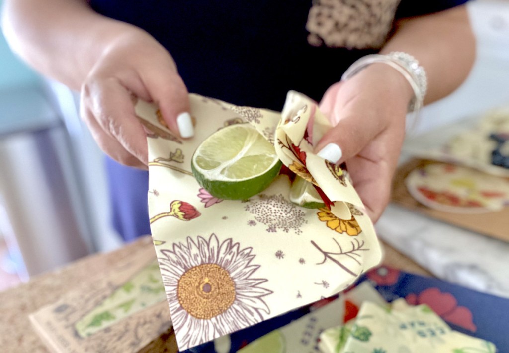hands holding floral bees wrap with half but lime inside
