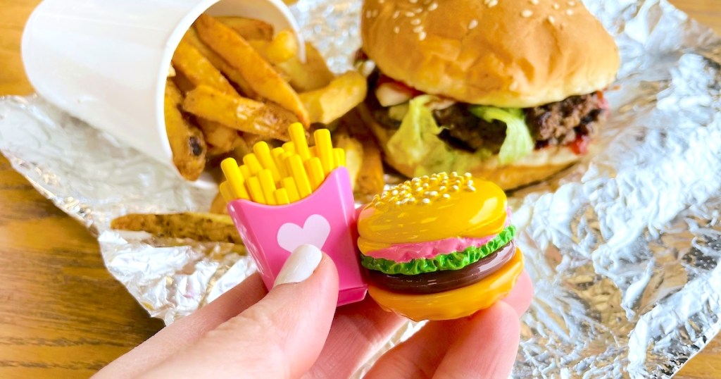 hand holding miniature fries and burger with five guys burgers in the background - April fools pranks