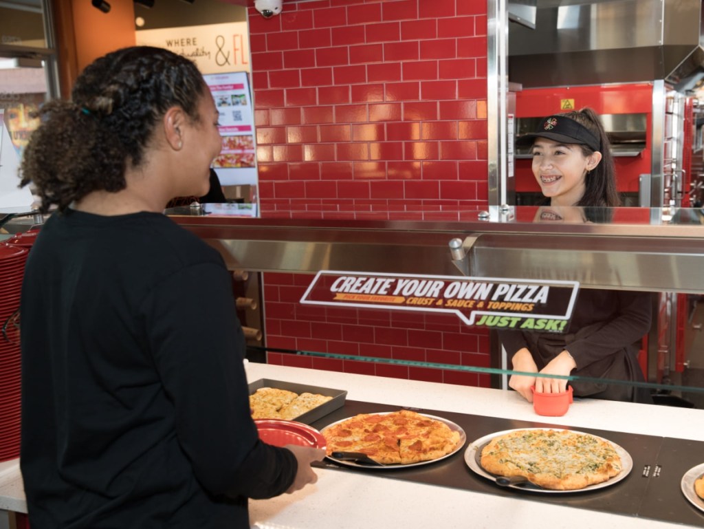 person getting pizza from buffet line