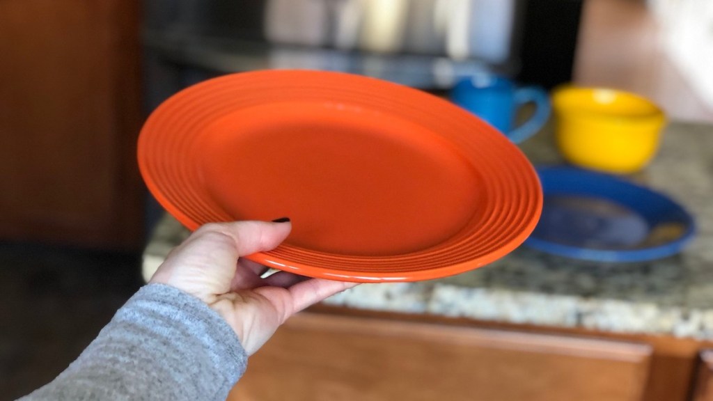 hand holding an orange plate in air