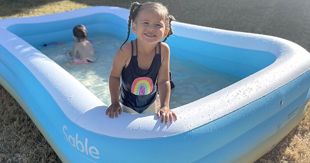 toddler standing in blue and white inflatable pool