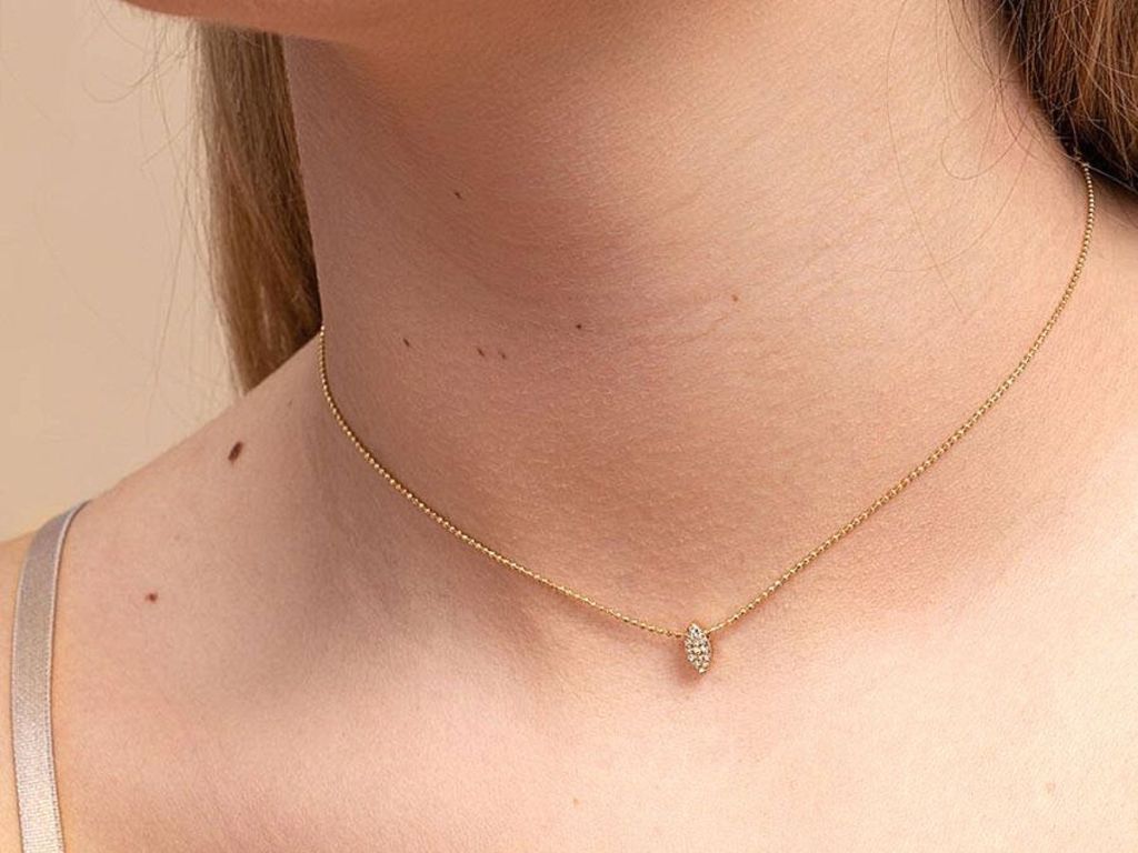 woman wearing gold necklace with diamond shape gem