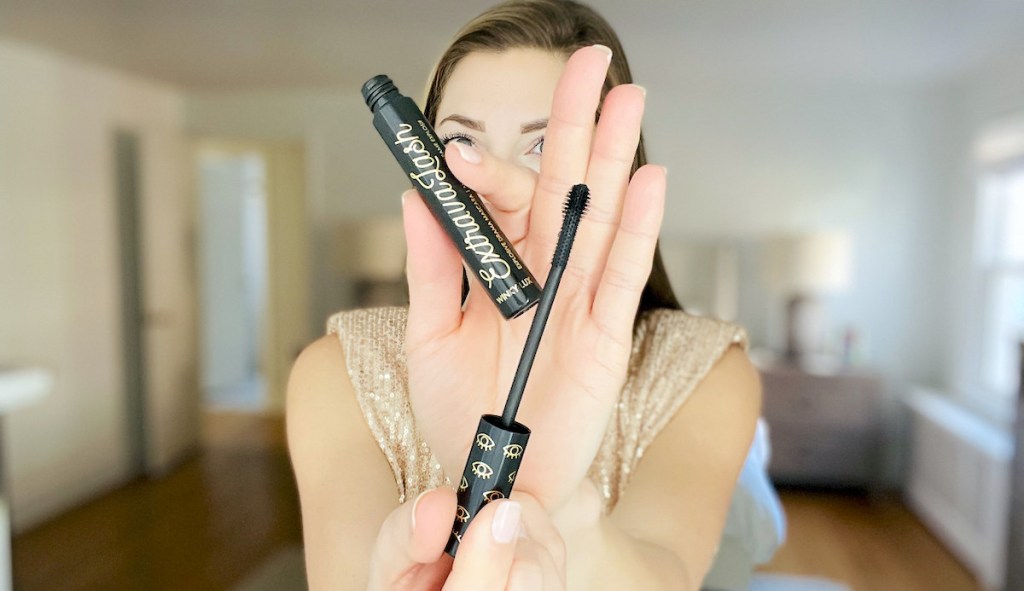 woman holding up tip of mascara brush 