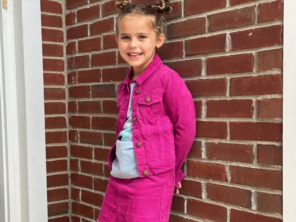 little girl standing against a brick wall