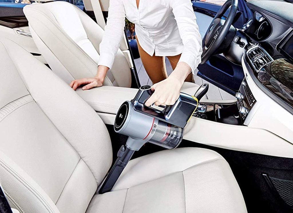 woman using handheld vacuum to clean car