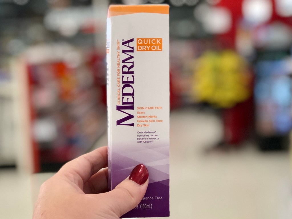 hand holding mederma quick dry oil at cvs