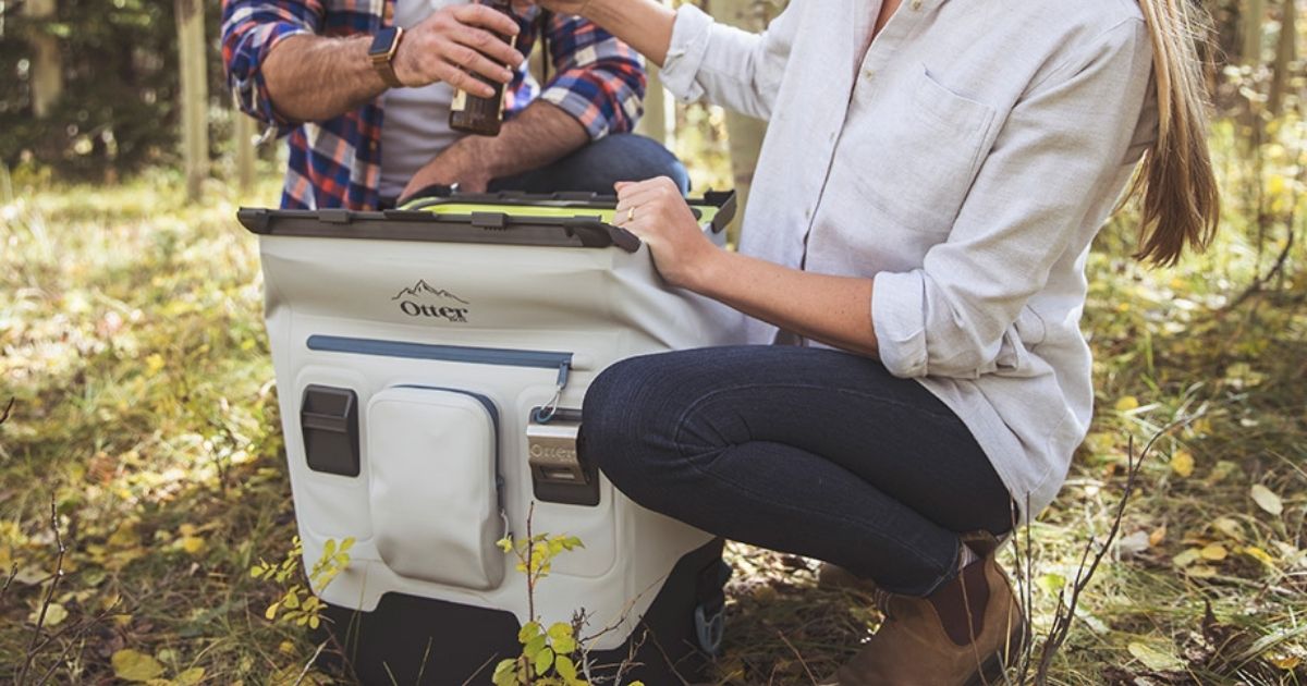 woman and man crouching down grabbing from white Otterbox cooler