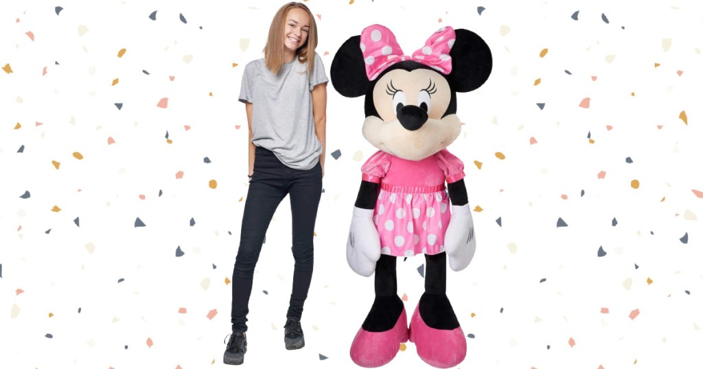 woman standing next to large minni mouse plush