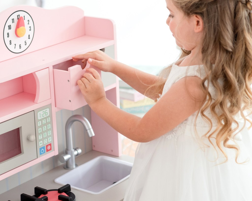 little girl playing with kitchen