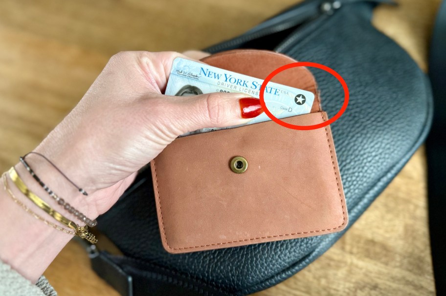 hand holding leather wallet with real id star circled in red