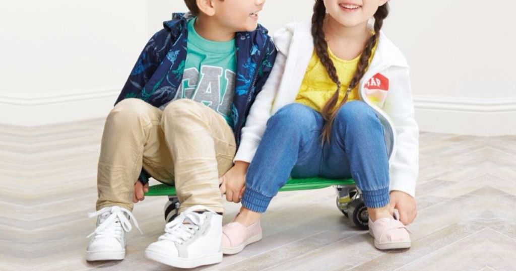 two kids sitting on a skateboard