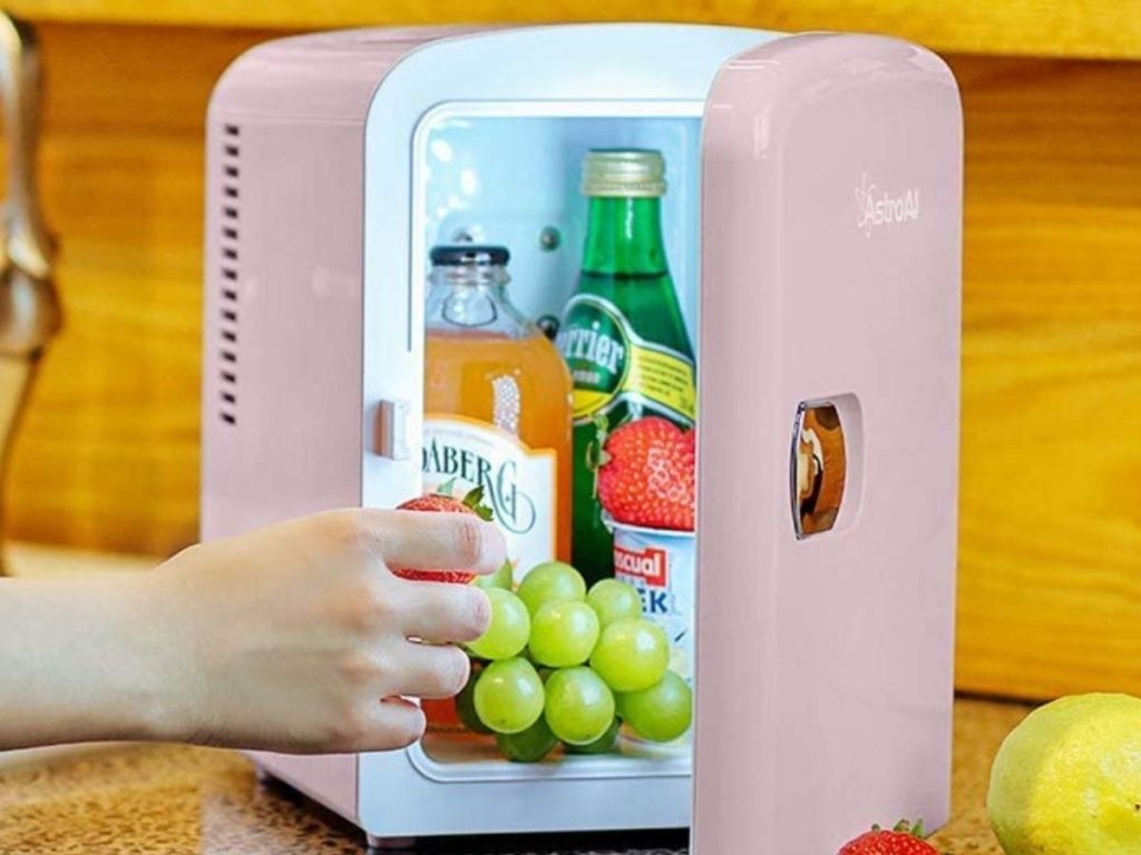 hand getting grapes from pink mini fridge