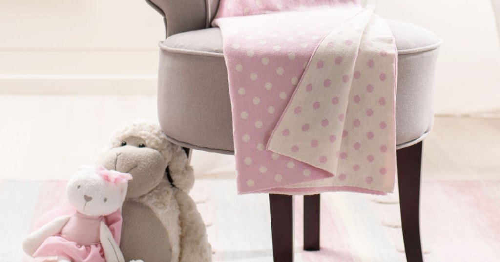 dotted baby blanket on chair next to stuffed animals