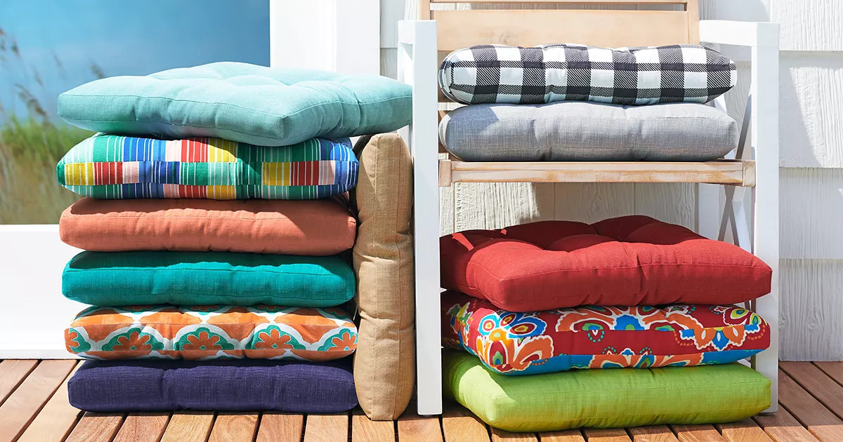 stacks of colorful outdoor pillows on and next to a chair on a deck