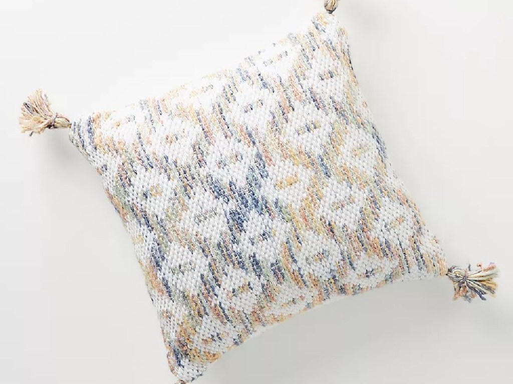 pillow with tassels and light colors woven through it