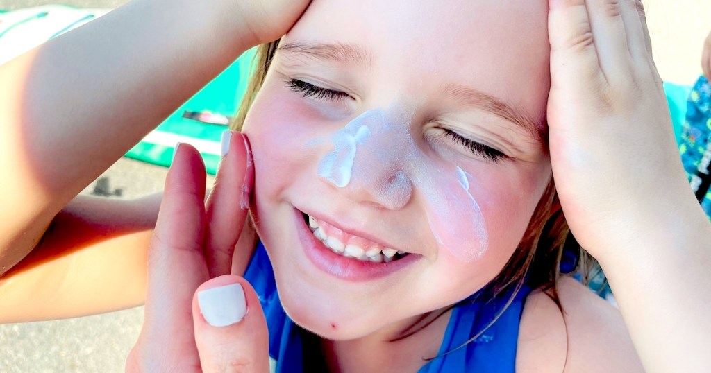 hand putting sunscreen on girls face