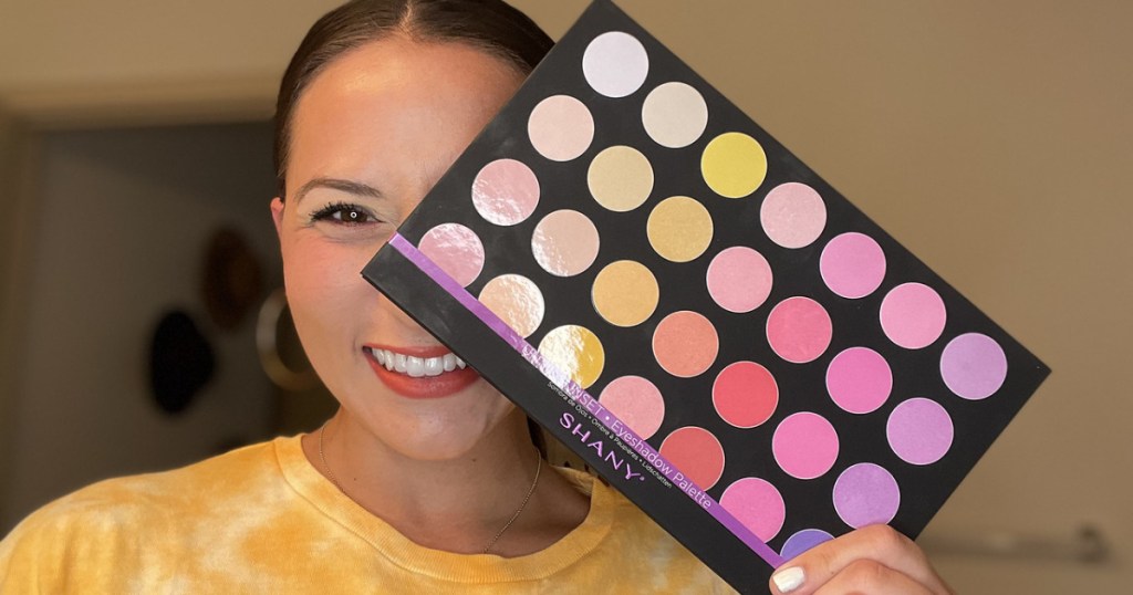 woman holding a large makeup palette in front of her face