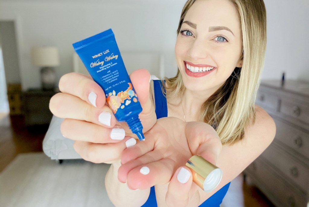 woman holding blue tube of winky lux eye cream