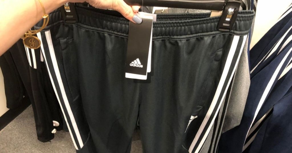 woman holding up hanger with men's Adidas shorts on it