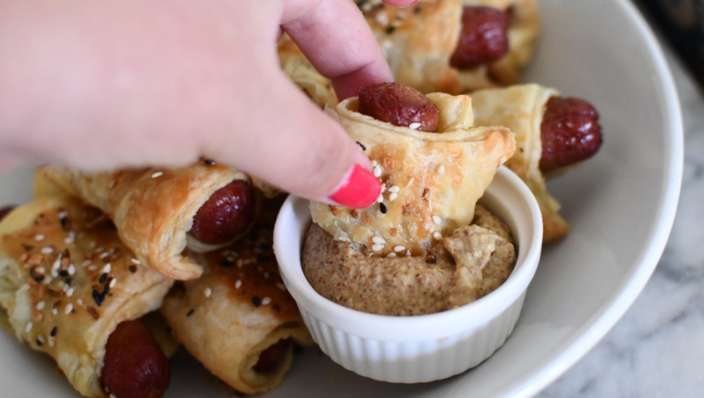 Dipping pigs in a blanket into brown mustard