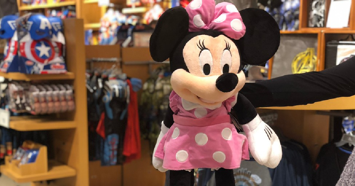 hand holding up a large pink and white minnie mouse plush doll in a store