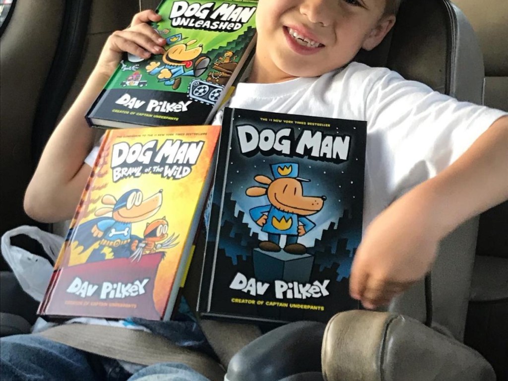 boy holding a variety of Dog Man books