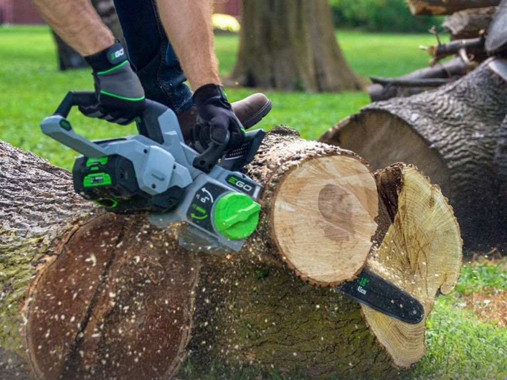 person using chainsaw on log