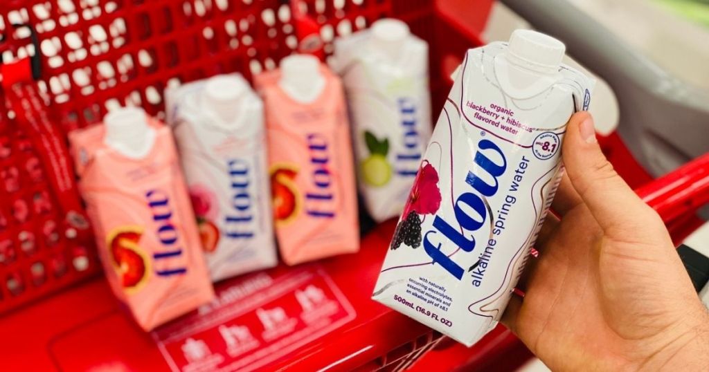 four Flow water in shopping cart basket at target with hand holding up one carton. 